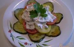 Готово! Сверху кусочки ли кружочки помидорчиков. И готовим заправку для салатика. Для этого сметану смешиваем с солью, чесноком, пропущенным через пресс, перцем молотый черным, зеленью. Перемешиваем. Выкладываем на салат, распределяем равномерно и подаем к столу пока огурцы еще теплые. Очень вкусно, по вкусу похоже на жаренные кабачки. Пробуйте. Приятного!