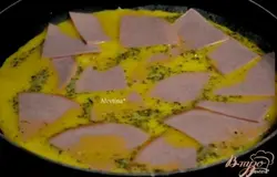 Растопить сливочное масло,обжарить слегка лук.Вылить яйца с пряностями. Выложить окорок или колбасу. Накрыть крышкой и жарить 9-11 мин.