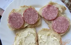 Колбасу нарезать кружочками. Выложить аккуратно на хлеб, два кружочка салями на один ломтик хлеба.