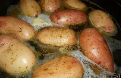 Картофель (желательно небольшой, одинакового размера) хорошо помыть. Прямо в кожуре сложить в толстостенную сковороду (лучше всего подойдет чугунная). Влить в сковороду бульон, чтобы он покрывал картофель на 3/4. Добавить перец, соль, оливковое и сливочное масло и щепотку кориандра.