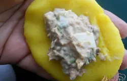 Из остывшего картофеля влажными руками слепить лепешку. В центр разместить начинку из рыбы.