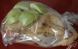 Внутрь поместить 1 яблоко, нарезанное крупными кусочками. Ломтики яблок сверху дополнительно пропитают птицу соком и ароматом, и хотя шкурка сильно потемнеет мякоть яблока превратится в сочное вкусное пюре. Скрепить ножки. Птицу на зашивала, т.к. хорошо скрепленные ножки позволяют начинке оставаться внутри. Положить птицу в пакет, сверху положить ломтики яблока мякотью вниз.