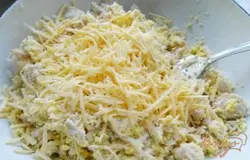 Добавить к желткам с курицей половину натертого сыра и майонез. Перемешать.