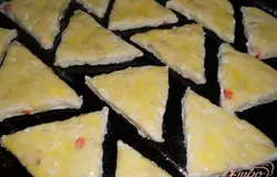 Замесить тесто картофельное (муки может понадобиться больше или меньше - зависит от картофеля). Раскатать (не тонко). Порезать на треугольнички. Выложить на смазанный противень и смазать желтком.