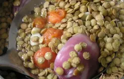 В кипящий бульон положить чечевицу, помидоры, порезанные кусочками, нарезанную на 4 части луковицу и крупно нарезанный чеснок.
