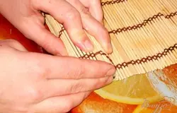 Кладем ролл на край коврика и пальцами рук приаккурачиваем края ролла, фиксируя начинку.