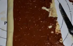 Второй кусок теста смажем шоколадной пастой, посыпем орехами и также свернем рулетом.