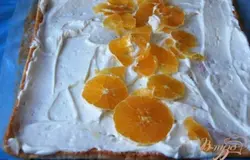 Развернуть рулет, промазать кремом, сверху выложить кусочки апельсина.