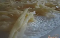 Сырой картофель натереть на терке, промыть в холодной воде и выложить на бумажное полотенце, чтобы впитались остатки воды.