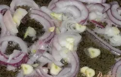 На растительном масле обжарить нарезанный лук полукольцами, добавить нарезанный чеснок,