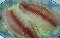 На лук выкладываем рыбу, которую посыпаем солью и специями.