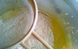 Постепенно просеивая сухую смесь, вводим в тесто