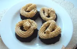 Мягкое сливочное масло взбить с вареным сгущенным молоком. Кулинарным мешком отсадить начинку на одну половинку. Прикрыть второй и украсить взбитыми сливками и кремом.