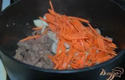 На растительном масле в казане обжарить свинину, добавить к мясу морковь и лук. Всё обжарить, протушить около 10 минут.