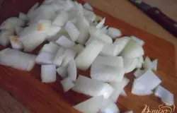 Пока курица обжаривается, очистить и нарезать лук крупными кусками.