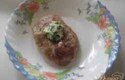Из фарша формируем лепешку, в середину которой кладем кусочек сливочного масла с зеленью.