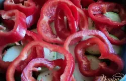 Перец почистить от семян, порезать кольцами и положить на кабачки.