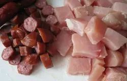Далее возьмём куриное филе и нарежем кубиками. Также нарежем охотничьи колбаски.