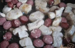 На сковороде с растительным маслом обжарим куриное филе до румяной корочки (около 10 минут), затем добавим колбаски и прожарим ещё пару минут. Шумовкой выложим филе и колбаски на тарелку.