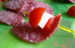 Накалываем на шпажку салями с одного края ломтика. Затем накалываем по кусочку перца и сыра, половинку помидорки и надеваем на зубочистку противоположный край ломтика. Повторяем со всеми нарезанными продуктами.