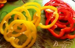 Порежьте болгарский перец кольцами (лучше выбрать трех разных цветов — это выглядит красочнее), предварительно удалив семена. Лук нарезать полукольцами, чеснок натереть на мелкой терке.