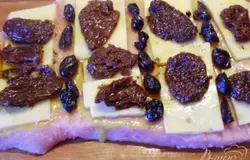 Разложить по мясу твёрдый сыр пластинками, вяленые помидоры и маслины.