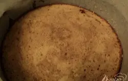 Установить на блюдо разъемное кольцо, бока выложить бумагой для выпечки. На дно положить пласт бисквита.